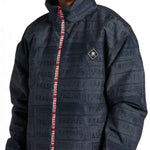 DC AW Vista Shell Jacket 2024 - A black jacket with a repeating pattern of "FRAGILE" labels in gray, featuring a red zipper and a small white logo on the left chest.