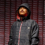 DC AW Vista Shell Jacket 2024 - A black jacket with a subtle pattern of white lines and logos, featuring a red zipper and a hood.