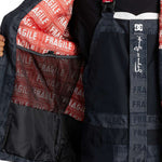 DC AW Vista Shell Jacket 2024 - A black jacket with a red zipper and white logo on the left chest.