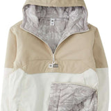 DC Women's Nexus Reversible Anorak Jacket 2024 - A tan and white jacket with a hood, featuring a zipper closure at the front.