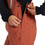 DC Women's Crusade Shell Bib Pant 2024 - A pair of burnt orange snow pants with a black zipper on the side.