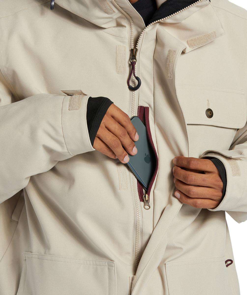 DC Servo Insulated Jacket - A cream-colored jacket with a black zipper and two chest pockets, one of which has a small black button on it.