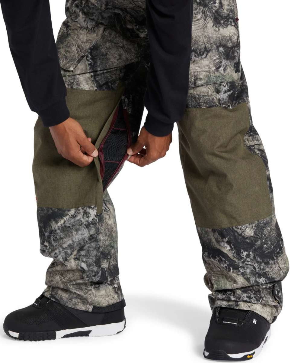 DC Shadow Shell Bib Pants 2024 - A pair of olive green snow pants with a subtle black and white marbled pattern on the lower legs.