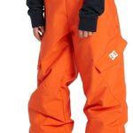 DC Youth Banshee Insulated Pant 2024 - A pair of bright orange snow pants with a white DC logo on the left leg, featuring two front pockets and adjustable Velcro straps at the waist.