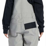 DC Youth Roadblock Insulated Bib 2024 - A pair of gray snow pants with a black strap on the back and a small pocket on the right side.