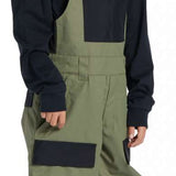 DC Youth Roadblock Insulated Bib 2024 - A pair of olive green and black insulated bib overalls with a white DC logo on the chest pocket.