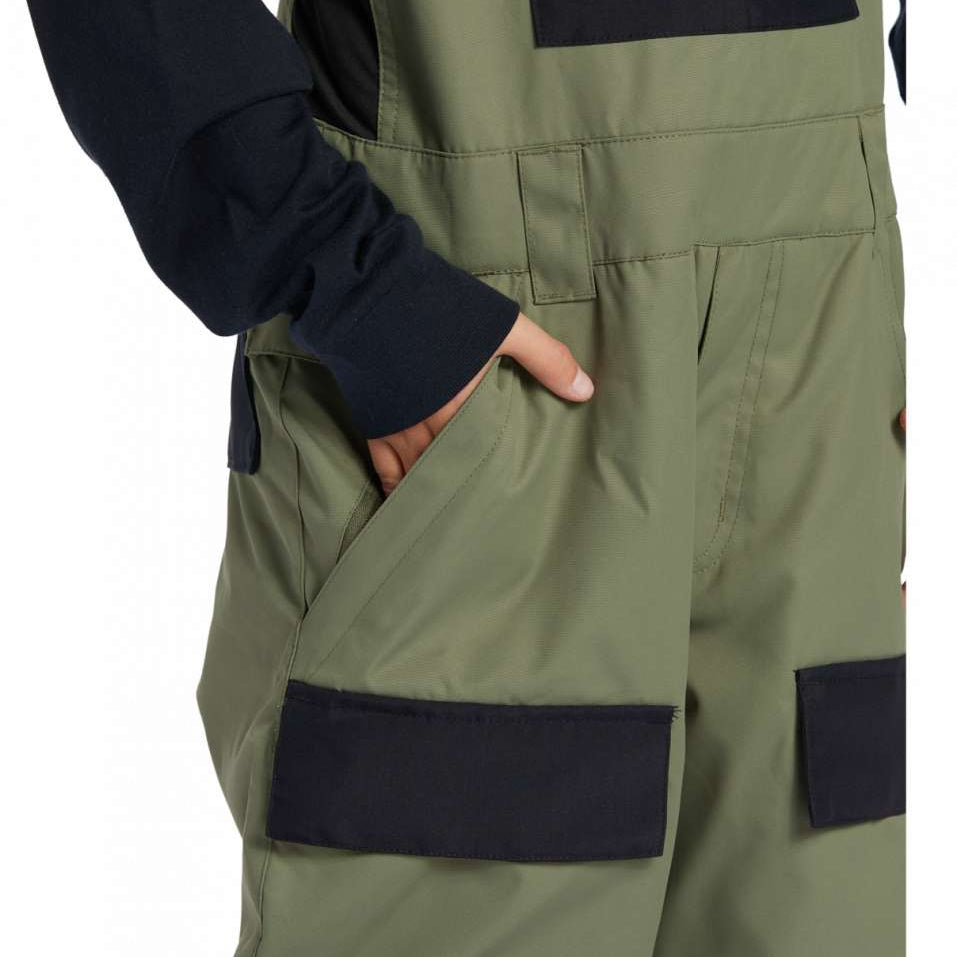 DC Youth Roadblock Insulated Bib 2024 - A pair of olive green insulated bib overalls with a black square patch on the right thigh and a black strap buckle on the left shoulder strap.