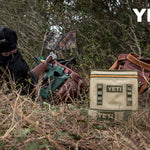 Yeti Hopper Flip 18 Personal Cooler - A tan cooler with a zipper and two handles, sitting on a wooden dock next to a boat.