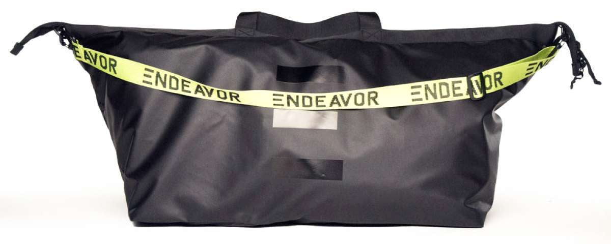 Endeavor Surplus Cargo Bag 2024 - A black duffel bag with a white logo and strap.