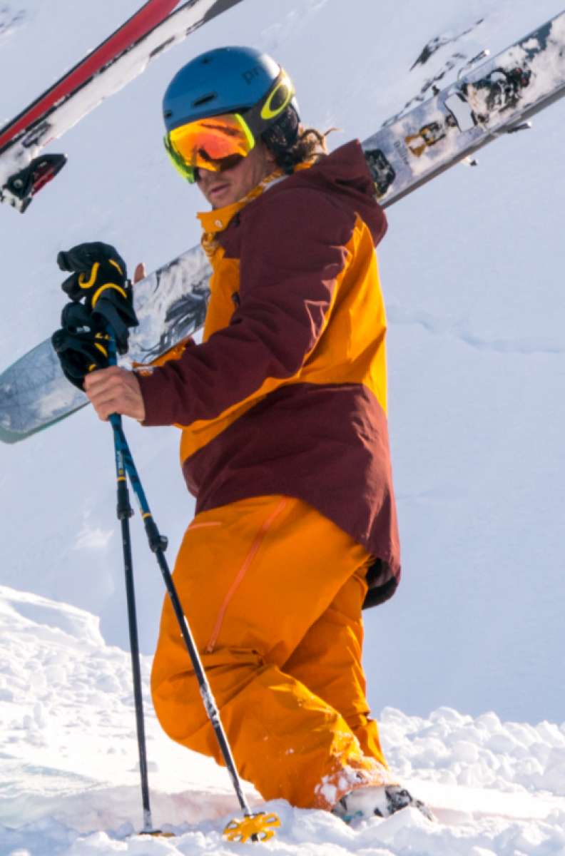 Flylow Lab Coat Shell Jacket 2022 - A black jacket with a high collar and zippered pockets, worn by a model on a snowy mountain slope.