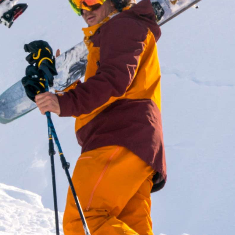 Flylow Lab Coat Shell Jacket 2022 - A black jacket with a high collar and zippered pockets, worn by a model on a snowy mountain slope.