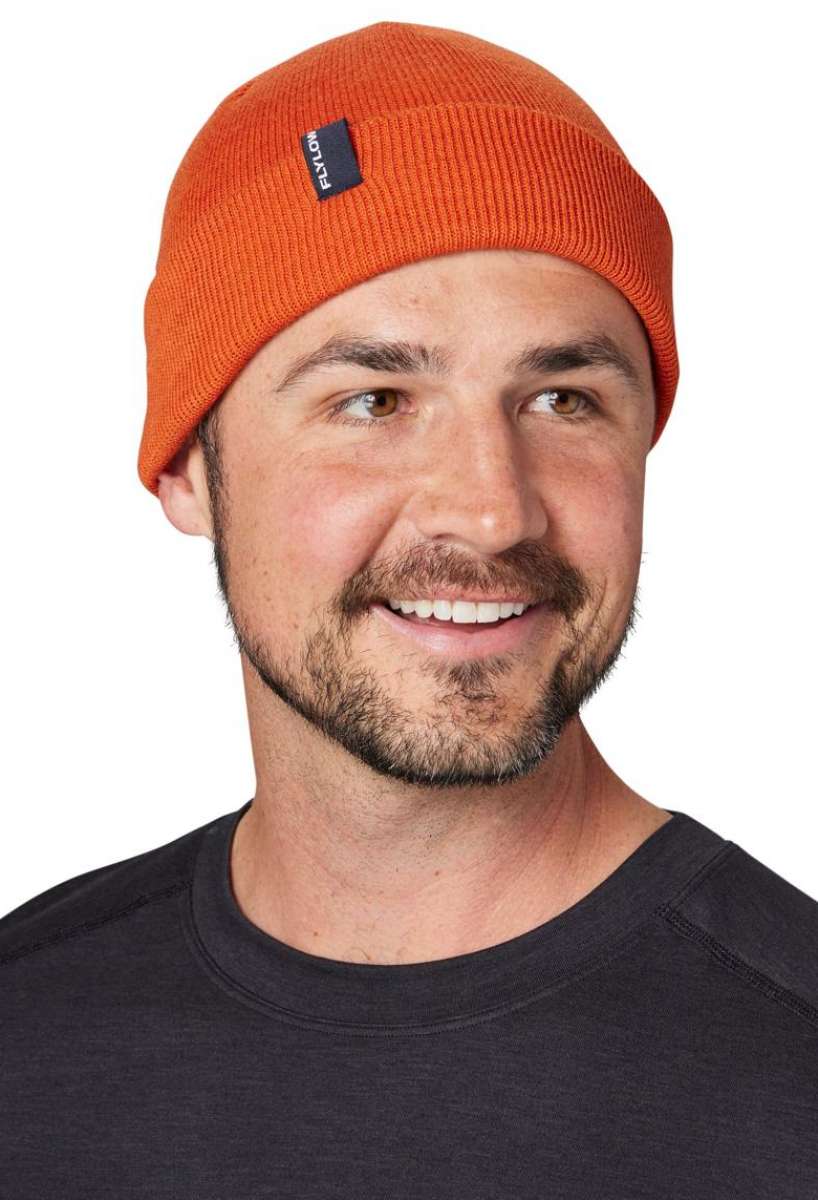 Flylow Longshoreman Beanie 2024 - A burnt orange beanie with a navy blue tag that says "FLYLOW" in white letters.