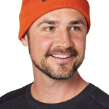 Flylow Longshoreman Beanie 2024 - A burnt orange beanie with a navy blue tag that says "FLYLOW" in white letters.