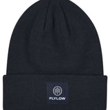 Flylow Longshoreman Beanie 2024 - A black beanie with a white logo featuring a mountain and trees in a circle, on the front.