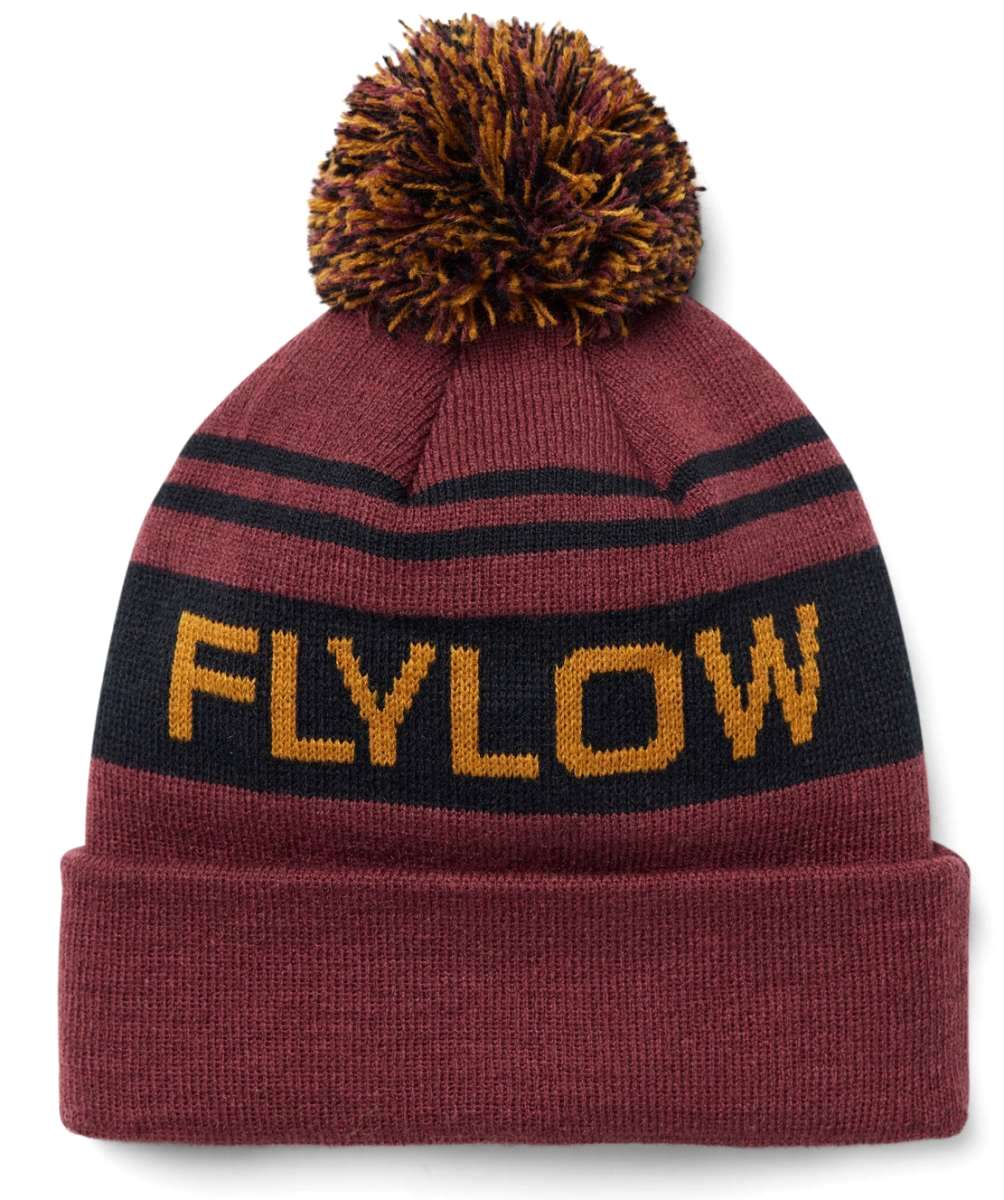 Flylow OG Pom Beanie 2024 - A maroon beanie with a large, multicolored pom-pom on top and two black stripes around it.