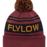 Flylow OG Pom Beanie 2024 - A maroon beanie with a large, multicolored pom-pom on top and two black stripes around it.