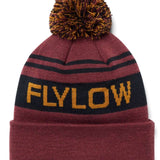 Flylow OG Pom Beanie 2024 - A maroon beanie with a large, multicolored pom-pom on top and two black stripes around it.