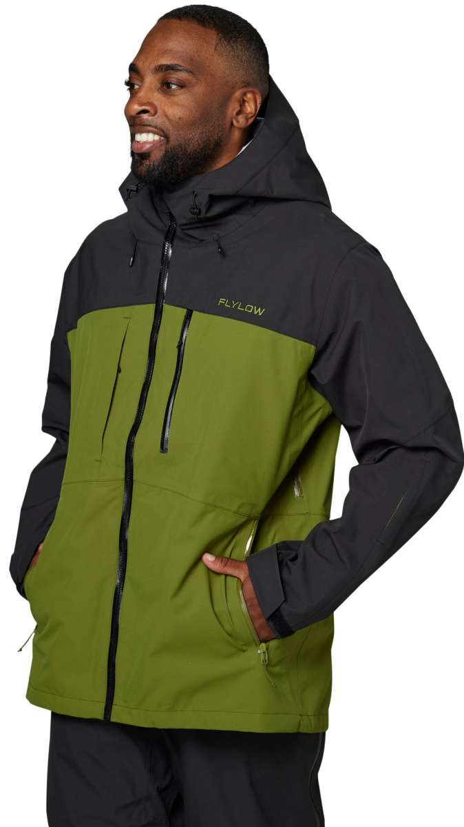Flylow Quantum Pro Shell Jacket 2024 - A black jacket with a green panel on the chest and a zippered pocket on the side.