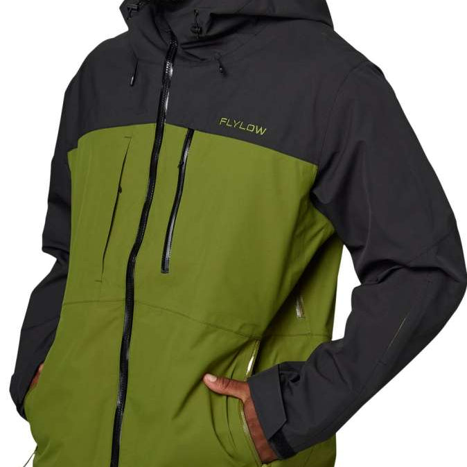 Flylow Quantum Pro Shell Jacket 2024 - A black jacket with a green panel on the chest and a zippered pocket on the side.