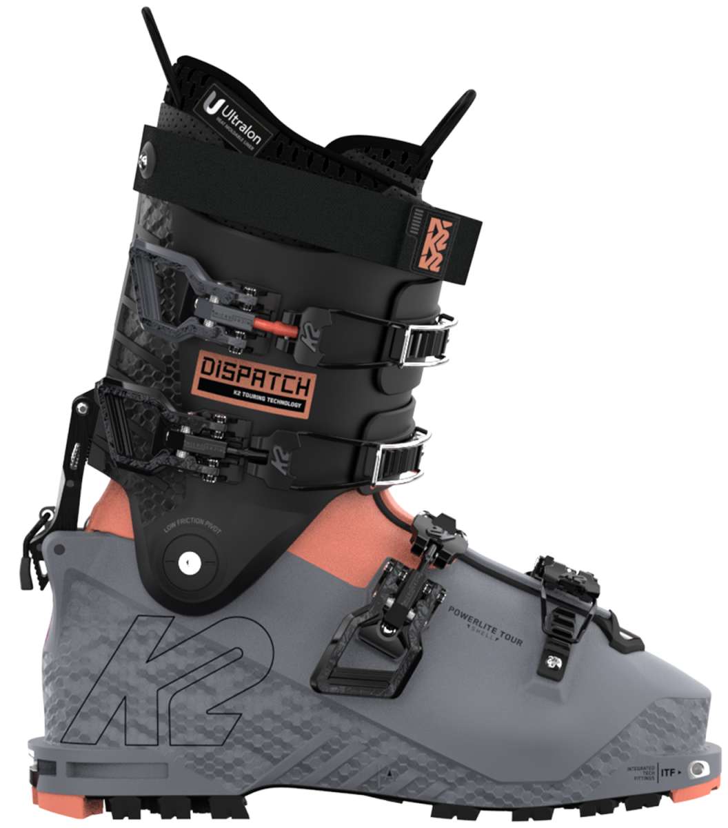 The image shows a pair of K2 Women's Dispatch 105 Ski Boots for the year 2023. The boots are gray and have orange accents, with a black buckle on the front. They appear to be designed for skiing and feature a sturdy construction with multiple straps and buckles for securing them to the skier's feet.