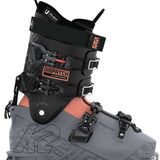 The image shows a pair of K2 Women's Dispatch 105 Ski Boots for the year 2023. The boots are gray and have orange accents, with a black buckle on the front. They appear to be designed for skiing and feature a sturdy construction with multiple straps and buckles for securing them to the skier's feet.