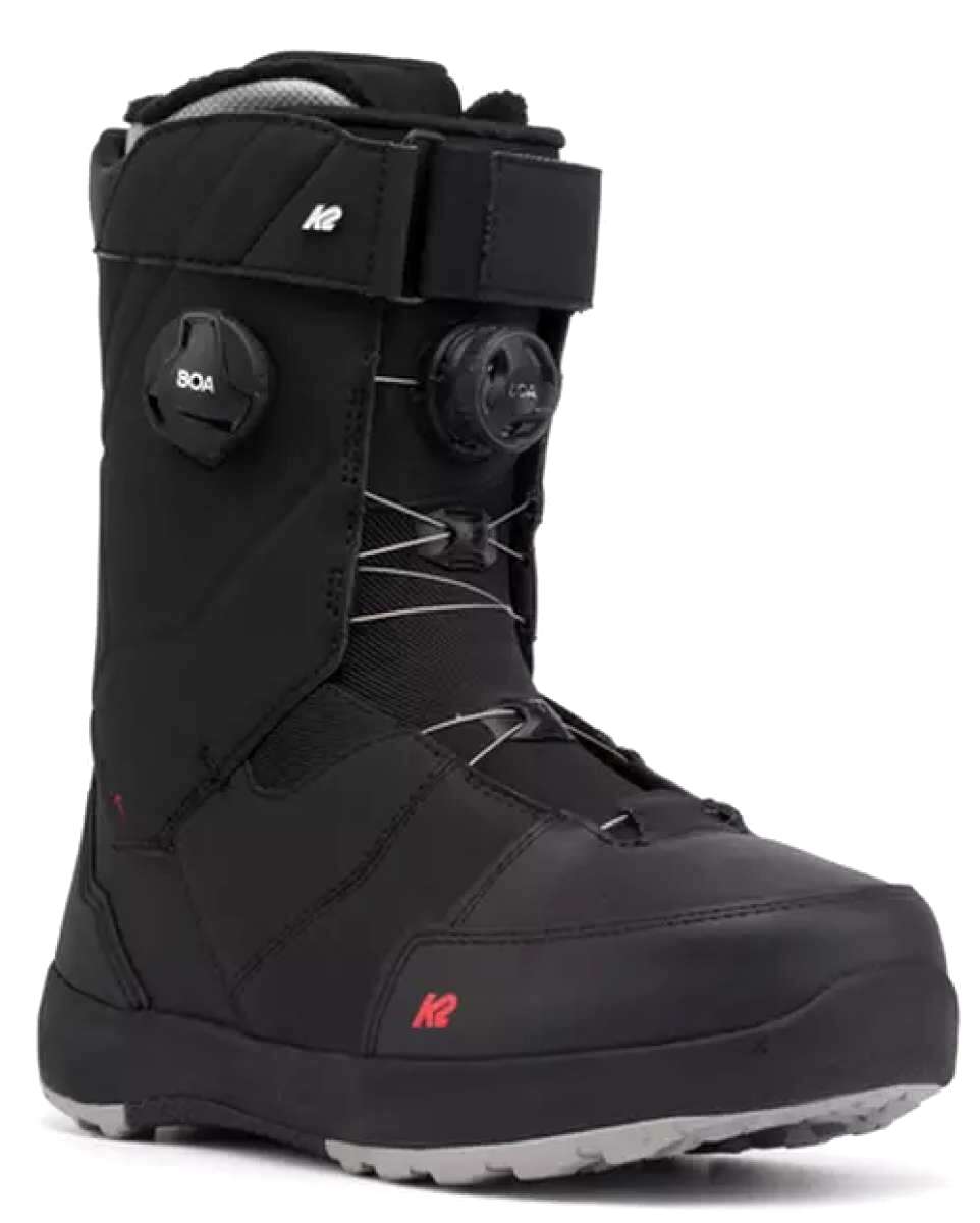 The image shows a pair of black snowboard boots with a white logo on the side. The boots have a thick, insulated design and are equipped with a buckle closure system for secure fit. They also feature a sturdy rubber sole for grip and durability.