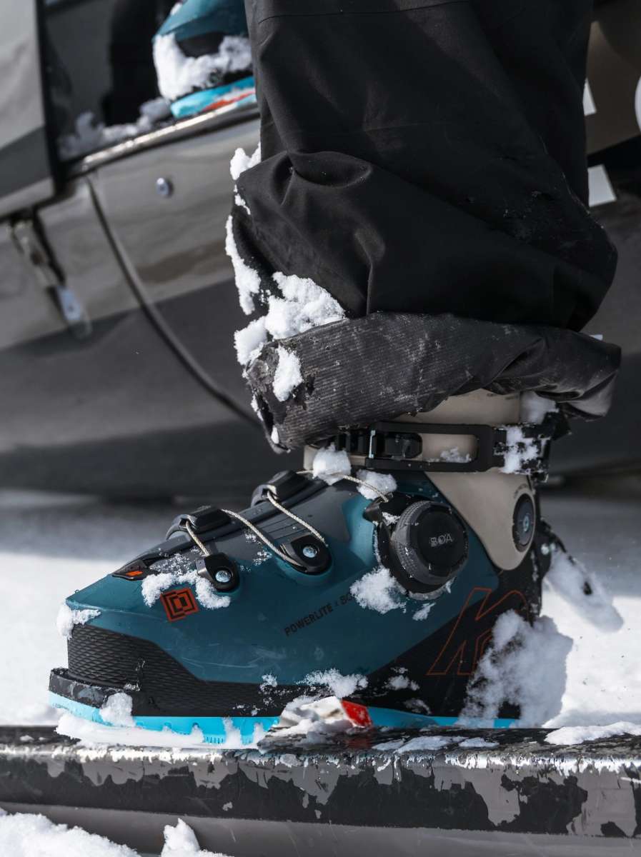 Blue K2 Mindbender 130 BOA ski boot sits in snow, showcasing its textured design and BOA closure system.