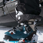 Blue K2 Mindbender 130 BOA ski boot sits in snow, showcasing its textured design and BOA closure system.