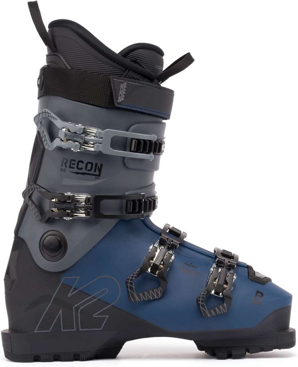 The image shows a pair of K2 Recon 90 MV ski boots for the year 2023. The boots are blue and black with silver buckles, straps, and hardware. They have a sturdy design with multiple adjustment points to ensure a secure fit.