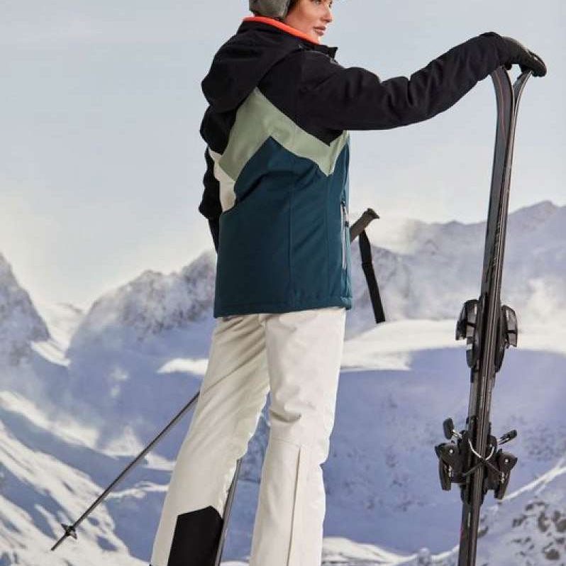 Killtec Ladies KSW 83 Peak Insulated Jacket - A dark blue jacket with a light green chevron pattern on the back, worn by a model in front of snowy mountains.