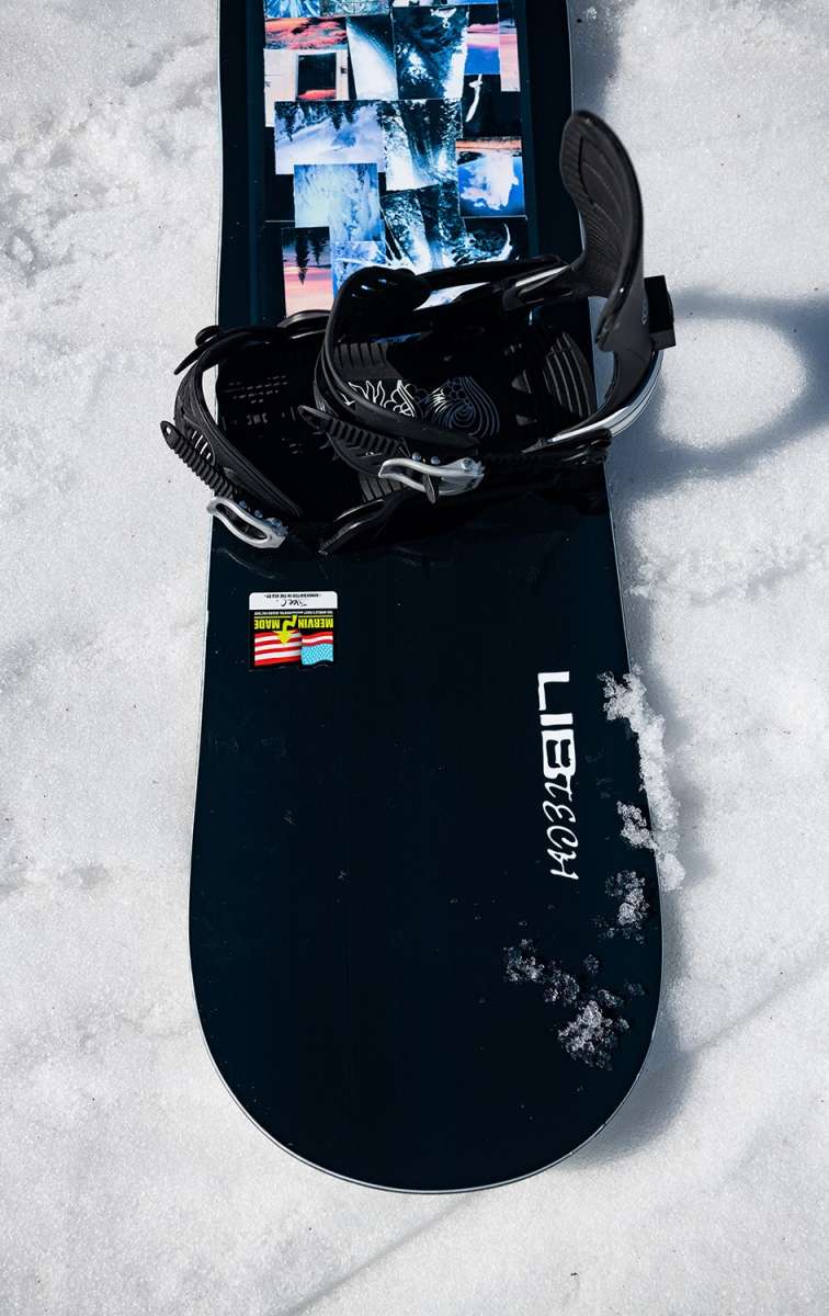 Lib Tech Skate Banana Snowboard 2024 B-Grade - A black snowboard with a blue and white graphic design featuring a banana shape, lying on its side in the snow.