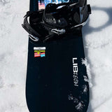 Lib Tech Skate Banana Snowboard 2024 B-Grade - A black snowboard with a blue and white graphic design featuring a banana shape, lying on its side in the snow.
