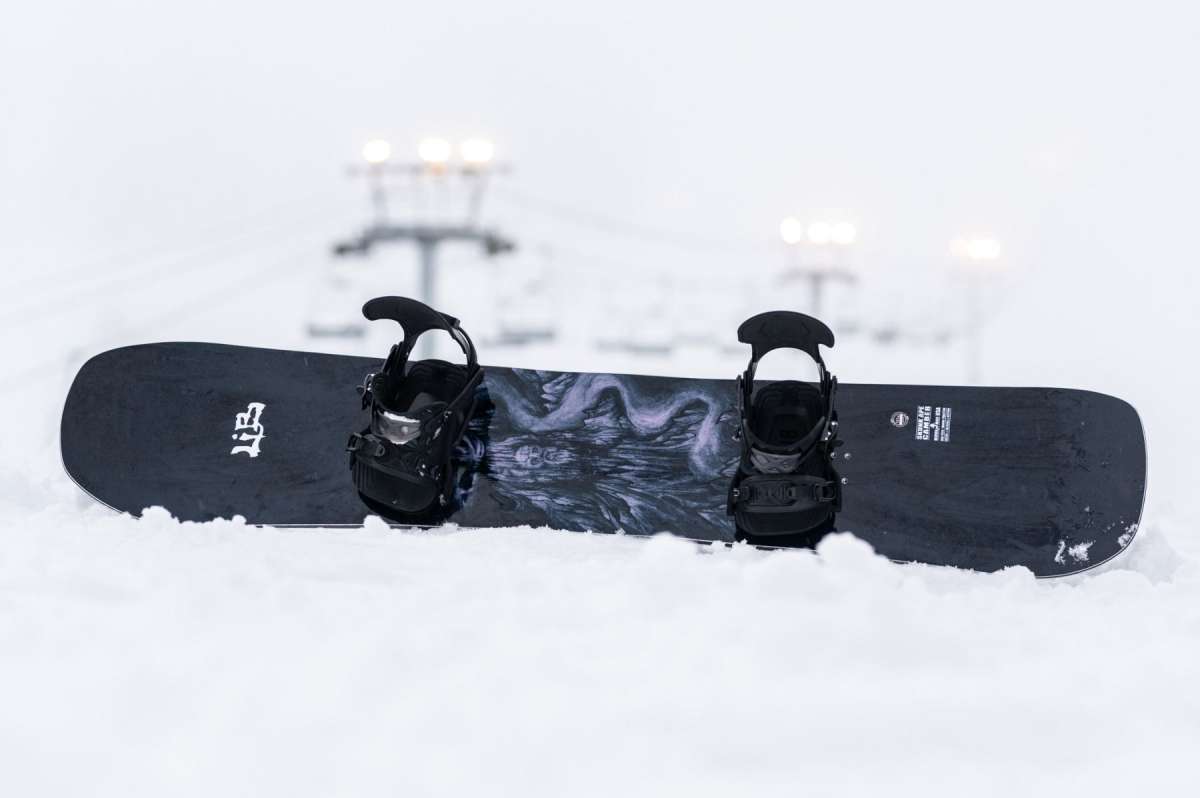 Lib Tech Skunk Ape Camber Snowboard - Black snowboard with white logo and abstract design on top of a snowy surface.