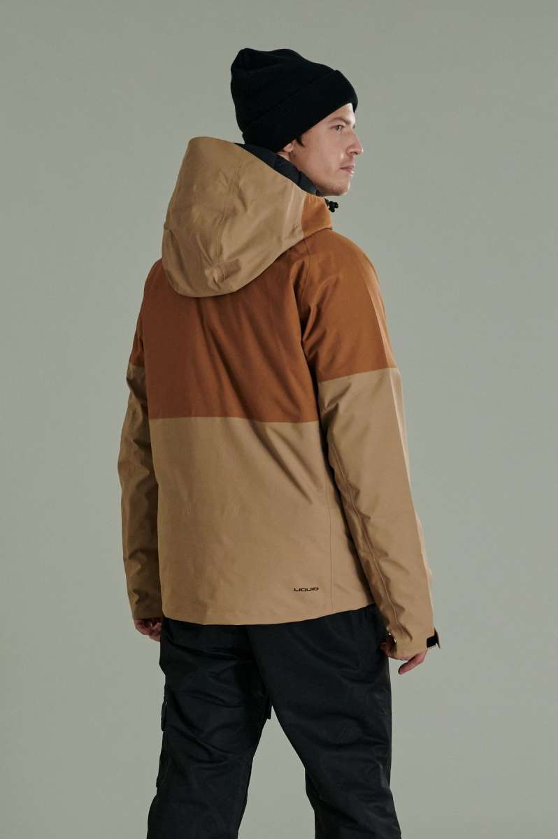 Liquid Anton Pro Stretch Jacket 2022-2023 - A tan and brown color-blocked jacket with a hood, worn by a model facing away from the camera.