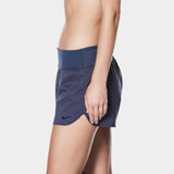Nike Swim Ladies' Solid Element Board Shorts Bottom Two-Piece Swimsuit - A woman wearing a two-piece swimsuit with navy blue board shorts and a matching top, posing in front of a gray background.