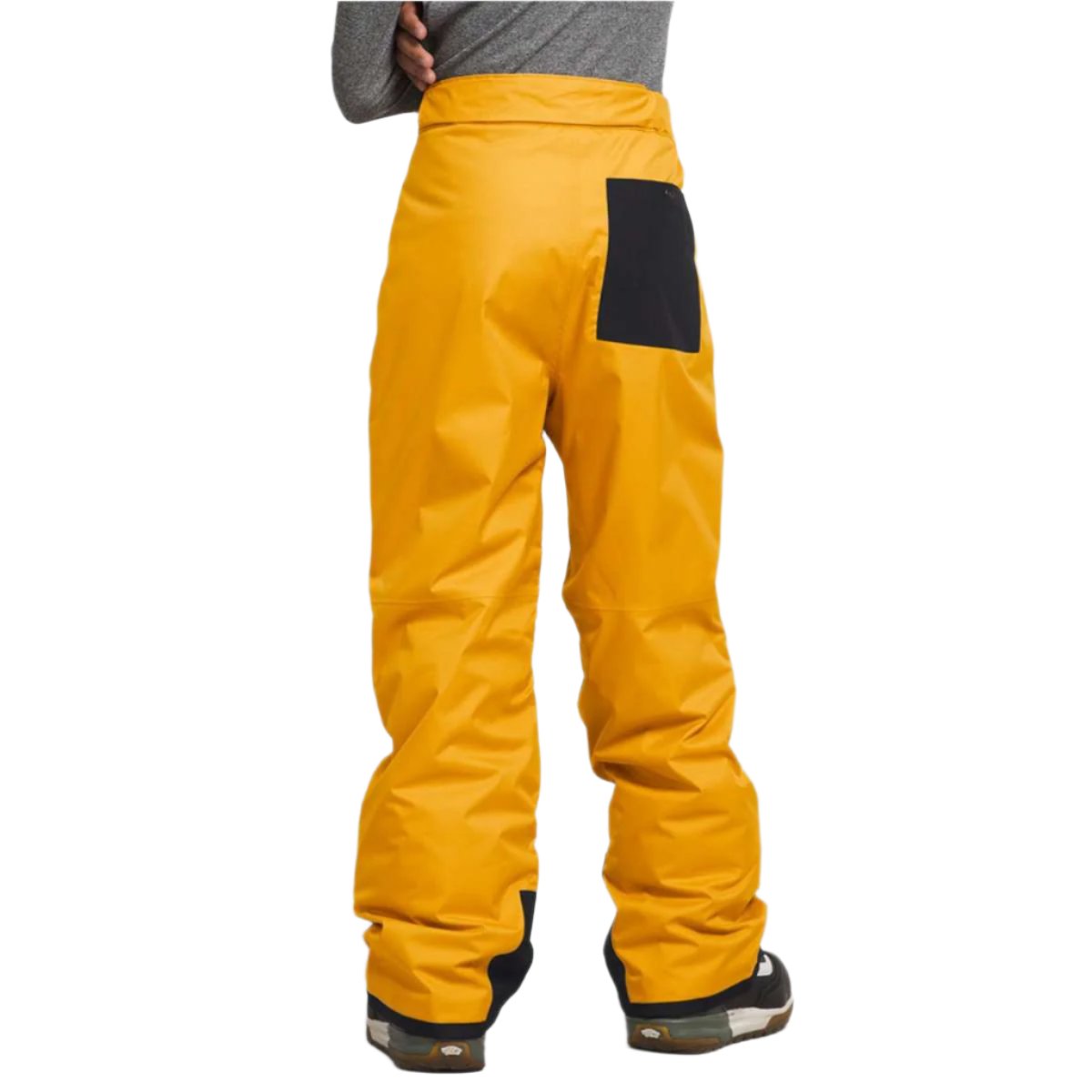 North Face Boys Freedom Insulated Pant 2024 - A pair of yellow snow pants with a black patch on the right side, featuring a solid color design and no visible patterns or textures.