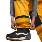 North Face Boys Freedom Insulated Pant 2024 - A pair of yellow and black insulated pants with a white stripe on the side, worn by an individual in a gray shirt.
