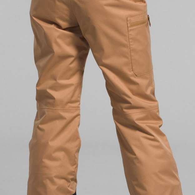 North Face Girls Freedom Insulated Pant 2024 - A pair of tan snow pants with a black waistband and white lettering that reads "THE NORTH FACE".
