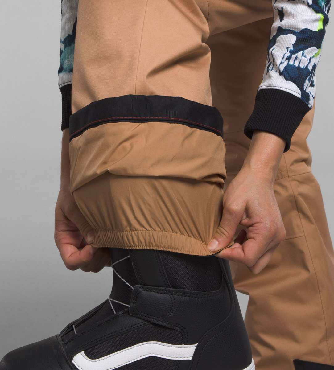 North Face Girls Freedom Insulated Pant 2024 - A pair of tan insulated pants with a black stripe at the top and a white logo on the left leg.