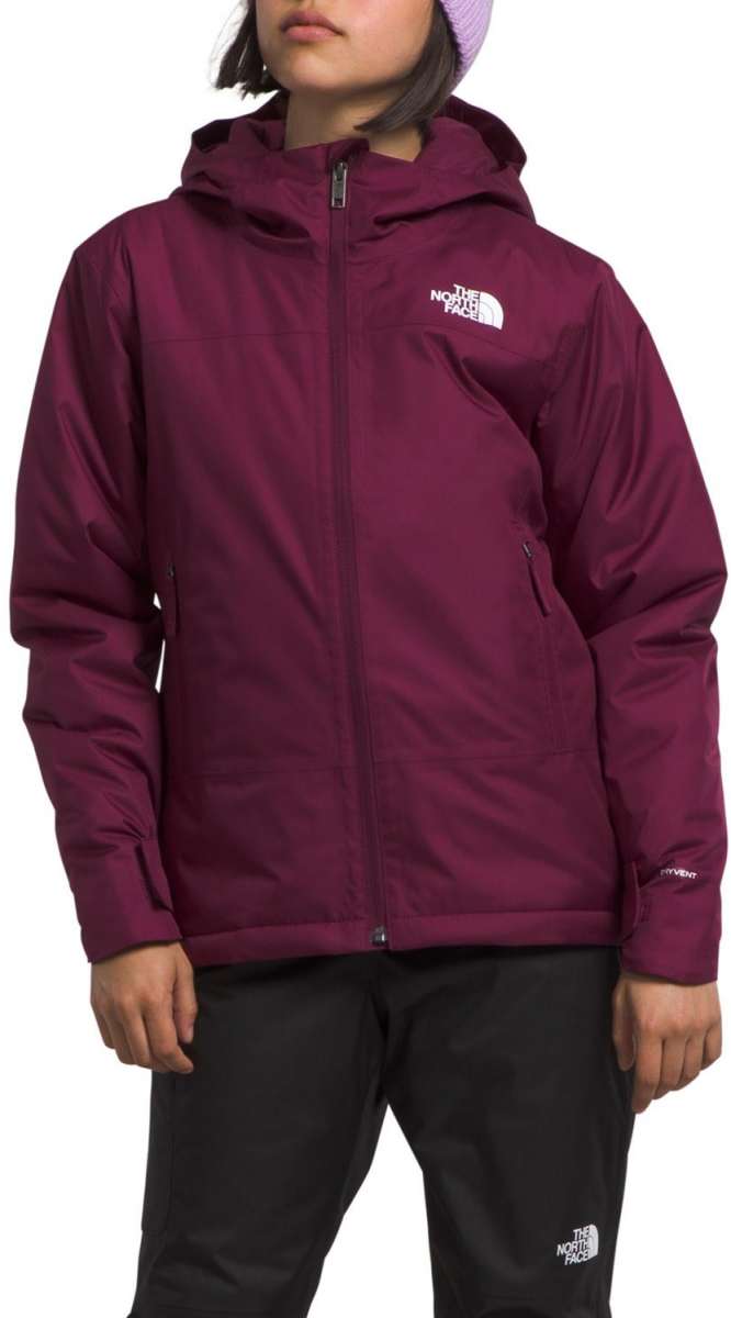North Face Girls Freedom Insulated Jacket - A young girl wearing a purple jacket with a white logo on the left chest and black pants, standing against a light gray background.