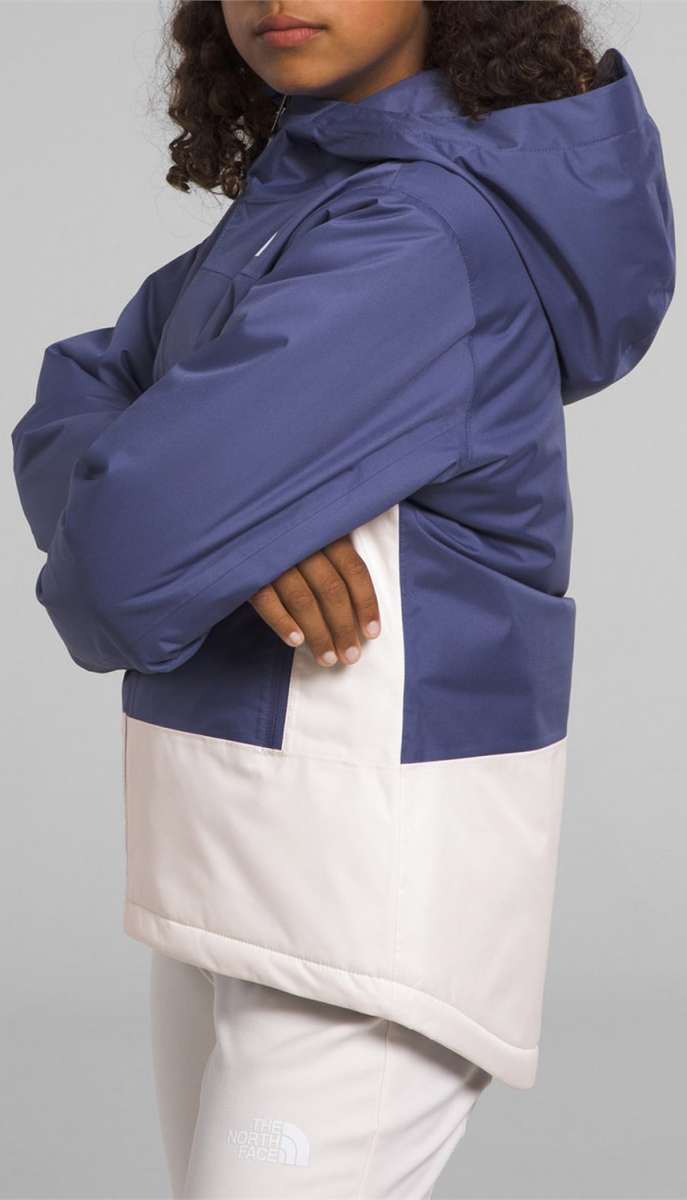 North Face Girls Freedom Insulated Jacket - A young girl with curly brown hair is wearing a blue and white jacket, posing in front of a light gray background.