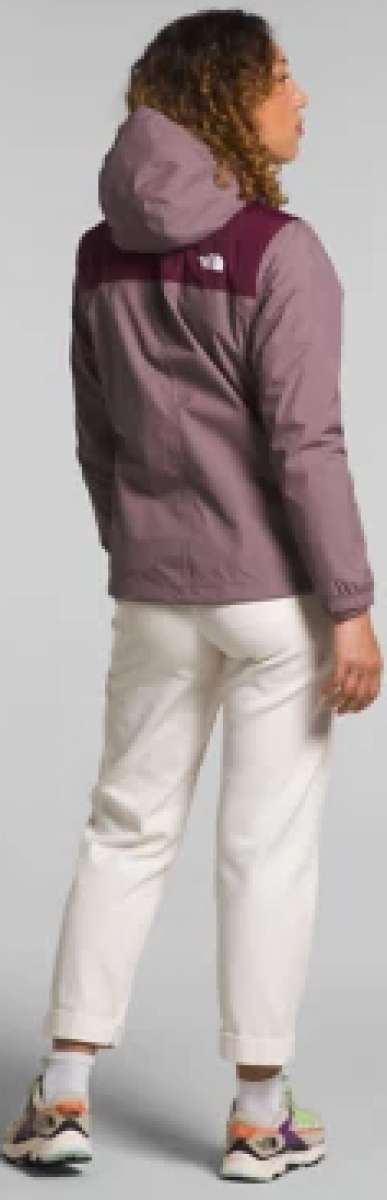 North Face Ladies Antora Triclimate Shell Jacket - A woman with curly brown hair and a purple jacket is facing left, wearing white pants and sneakers.