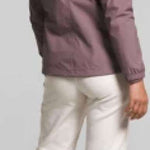 North Face Ladies Antora Triclimate Shell Jacket - A woman with curly brown hair and a purple jacket is facing left, wearing white pants and sneakers.