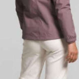 North Face Ladies Antora Triclimate Shell Jacket - A woman with curly brown hair and a purple jacket is facing left, wearing white pants and sneakers.
