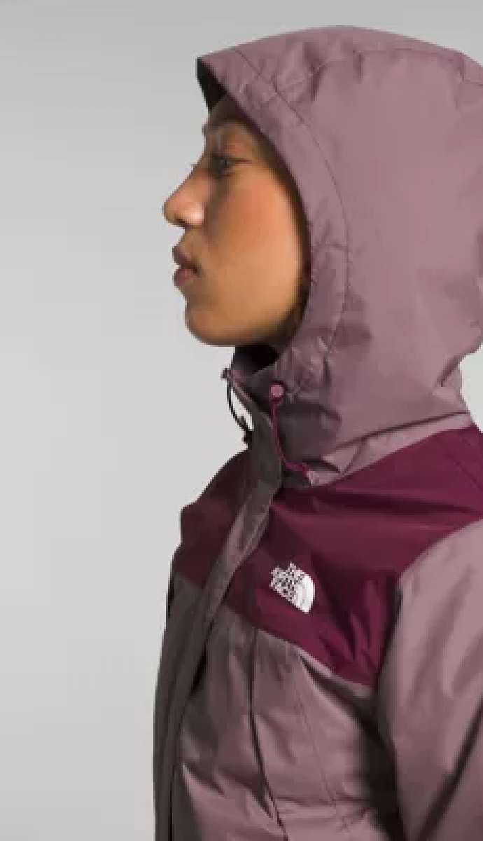 North Face Ladies Antora Triclimate Shell Jacket - A woman wearing a purple and grey jacket with a white logo on the left chest area, standing in front of a light gray background.