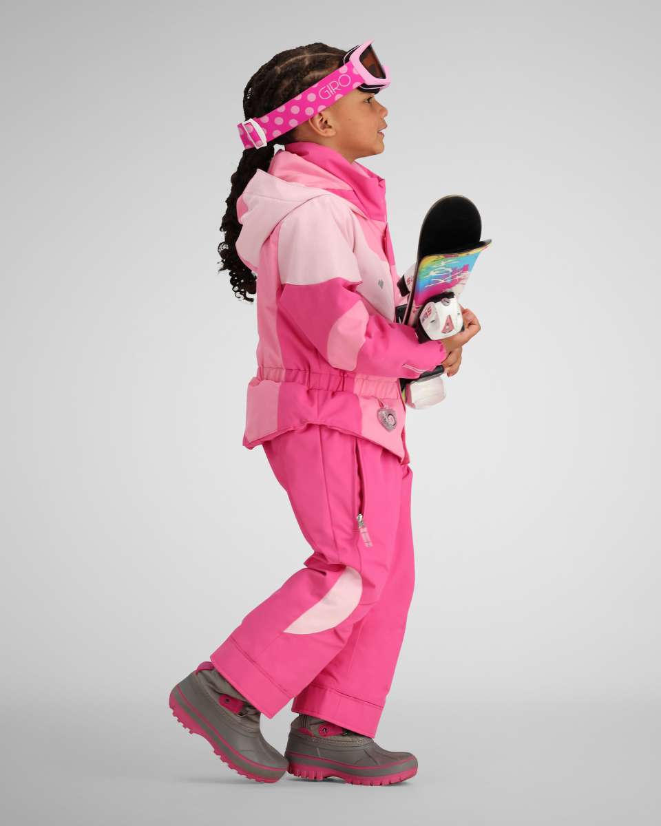 Obermeyer Kids Swirliana Insulated One Piece Suit 2024 - A pink snowsuit with a swirly pattern on the chest and sleeves, worn by a young girl holding a snowboard.