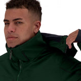 Obermeyer Kodiak Jacket 2022 - A dark green jacket with a high collar and zippered pockets, worn by a man with short curly hair looking to his left.