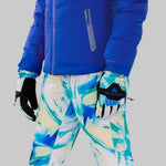 Obermeyer Women's Cosima Down Jacket - A royal blue down jacket with a high collar and zippered pockets, featuring a black logo patch on the left sleeve.