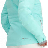 Obermeyer Women's Cosima Down Jacket 2024 - A woman with long dark hair wearing a light blue down jacket and white pants, facing left.