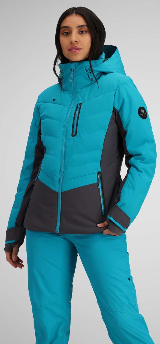 Obermeyer Women's Cosima Down Jacket - A bright blue down jacket with a high collar and zippered pockets, featuring a black logo patch on the left sleeve.